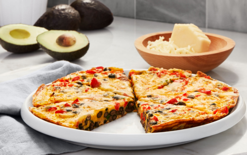 Plate of quiche on countertop with cheese and avocado