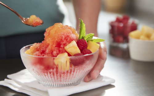 Frozen ice desserts topped with syrup and chopped fruits