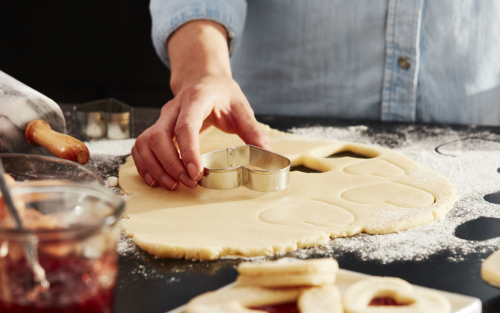 Woman cutting out cookies with a heart-shaped cookie cutter