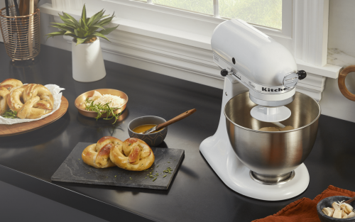 White stand mixer next to cutting board and platter with soft pretzels