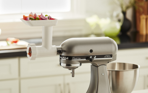 Food in tray of KitchenAid® Food Grinder attached to stand mixer