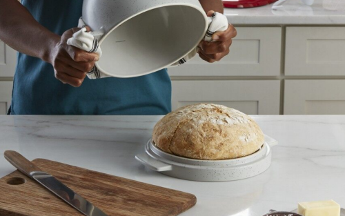 Loaf of bread next to a wooden cutting board and knife