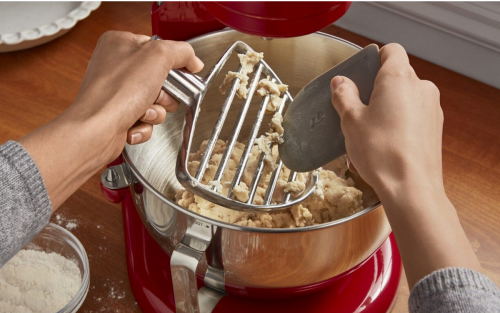 Person scraping dough off a stand mixer attachment