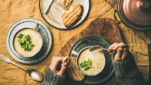 A woman enjoying a bowl of creamy soup with a side of toasted bread.