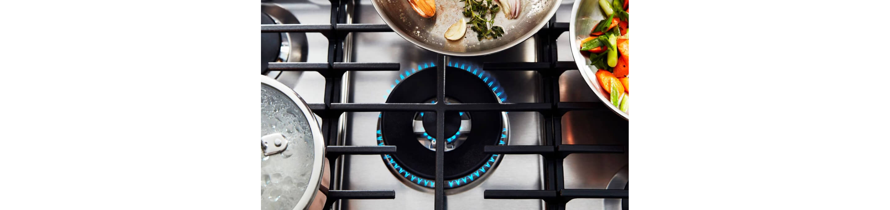A variety of pans arranged around a lit gas burner.