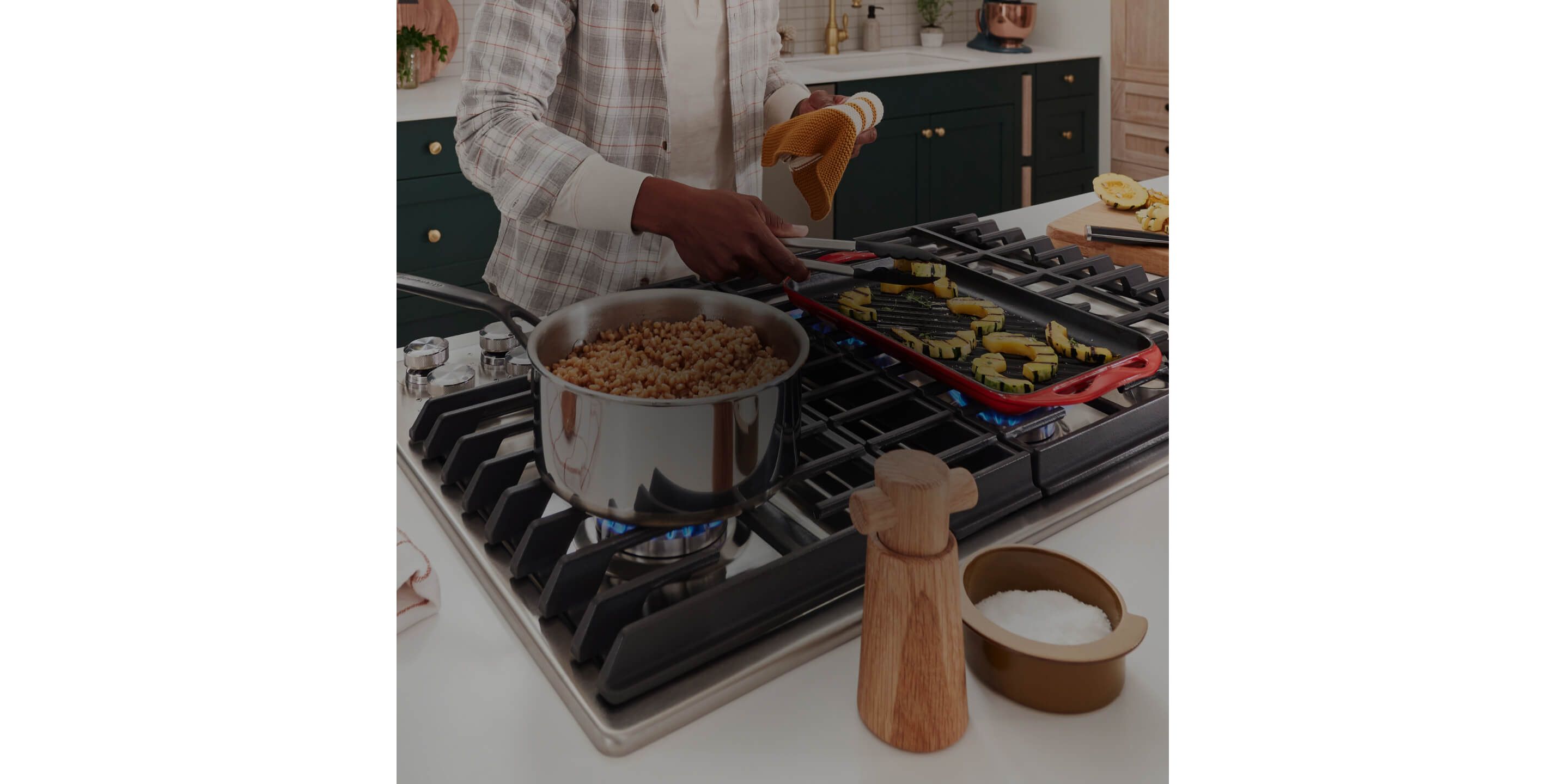 A person cooking multiple dishes on a gas cooktop.