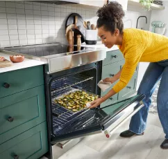 A person pulling food out of the oven.