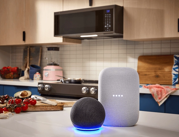 Two smart devices sitting on a counter, with a KitchenAid® Microwave in the background.