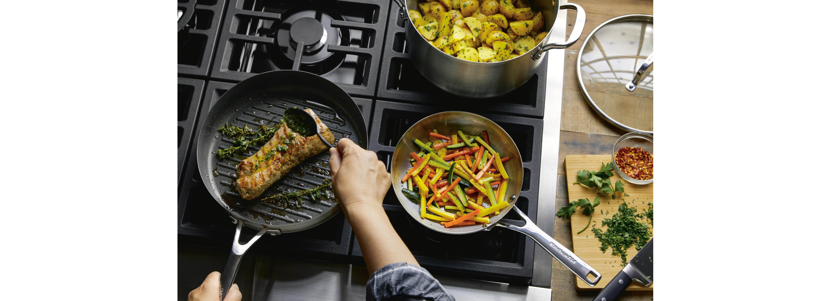 A person cooking with a stainless steel 3-ply base pan.