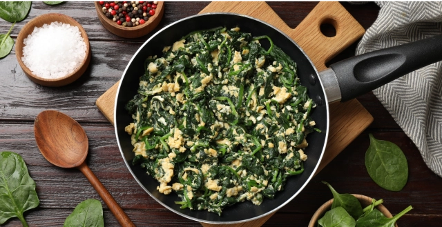 A skillet filled with cooked spinach and ground chicken.