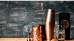 A set of copper cocktail shakers on a wooden counter.
