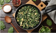 A skillet filled with cooked spinach and ground chicken.