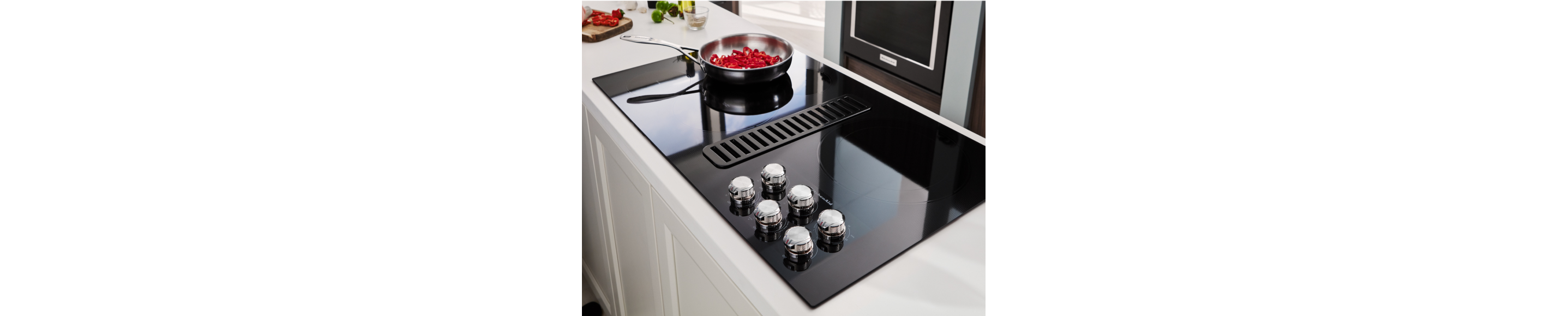 Peppers cooking on an electric cooktop on a kitchen island.