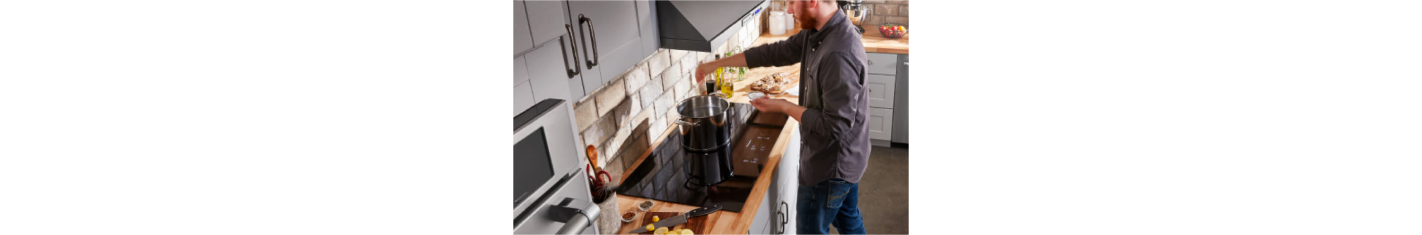 Person adding seasoning to a large pot on a black KitchenAid® cooktop