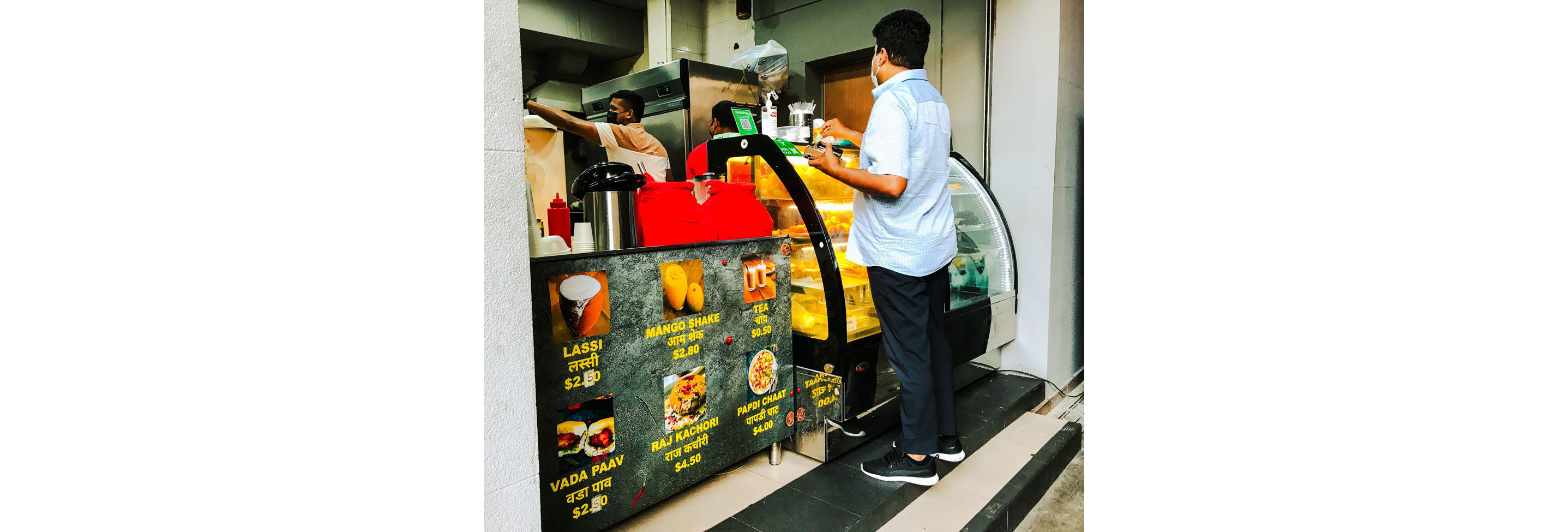 A person ordering food at a small Indian food stall.