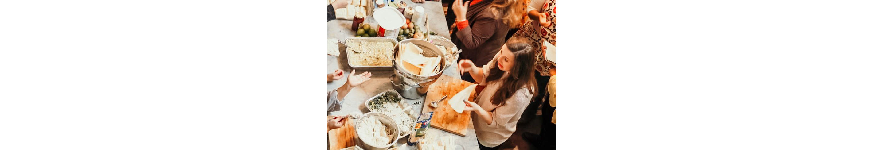 A large family working together over a kitchen counter.