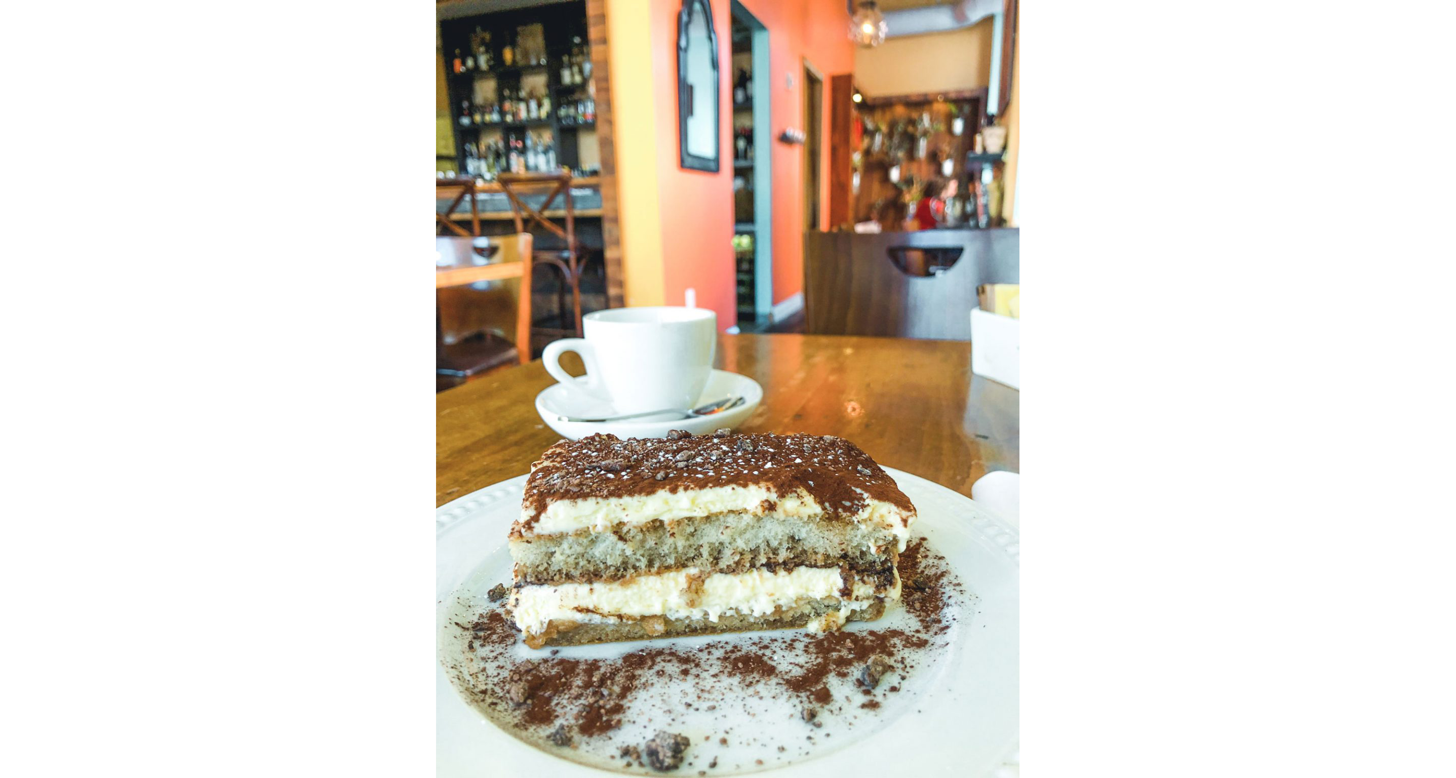 A slice of tiramisu resting on a white dish.