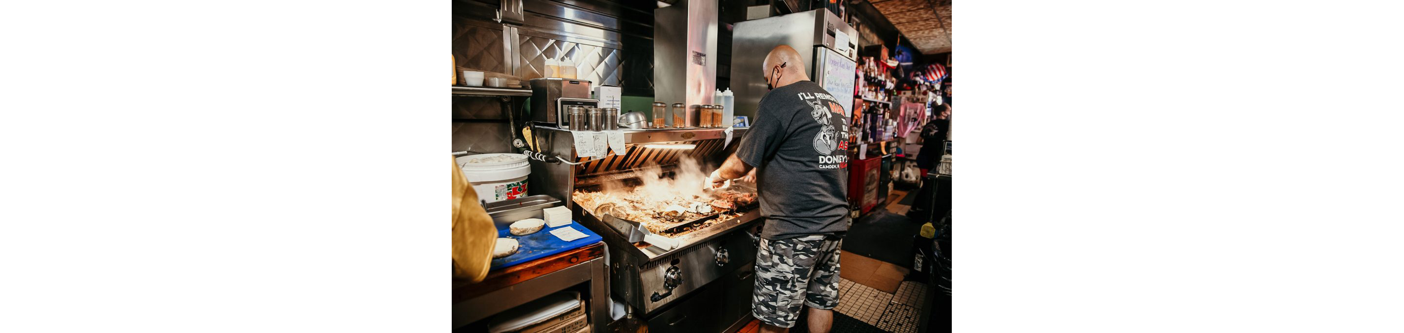 A person working diligently working at the grill at Donkey's Place.