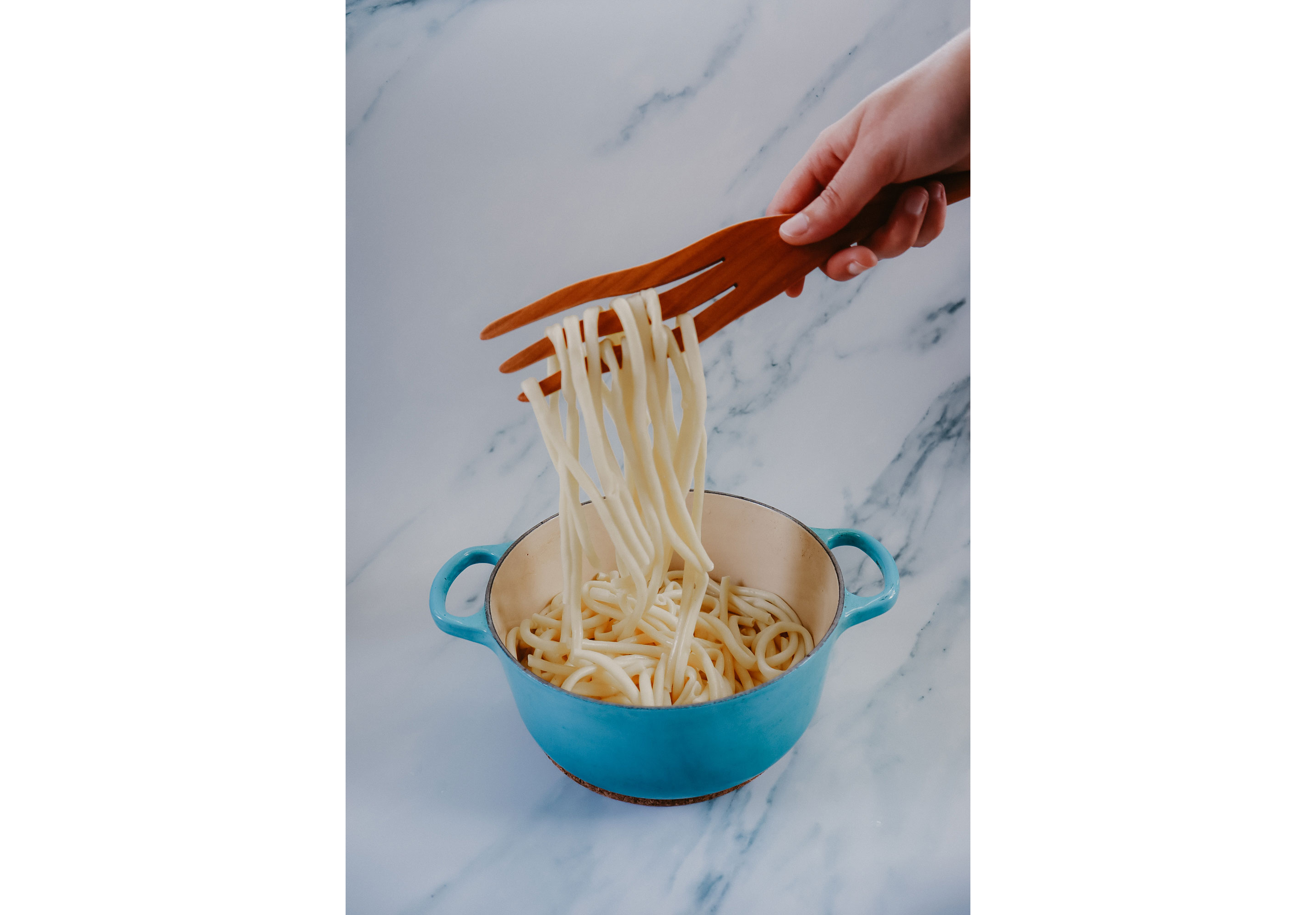 A wooden fork entangling noodles.