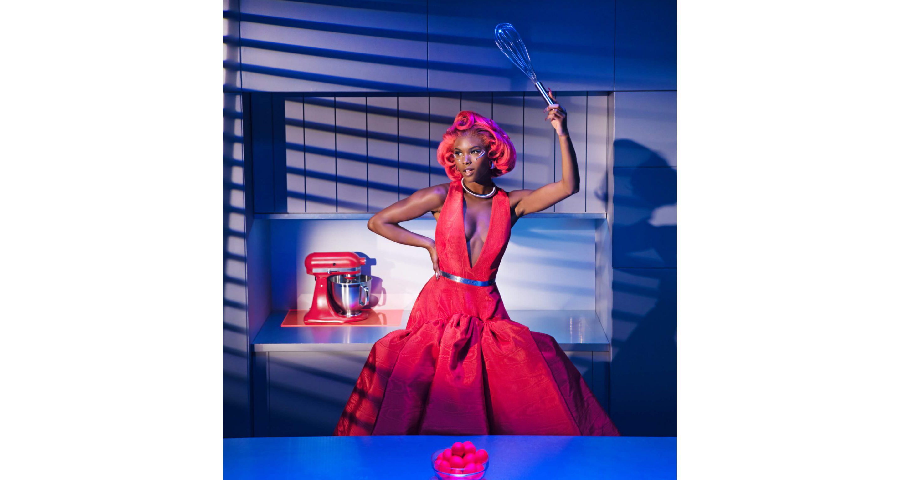 A model posing in a kitchen wearing Look Ten while holding a cooking tool near the Artisan® Series Stand Mixer on the countertop and a close-up of the KitchenAid® trim band on a model. 