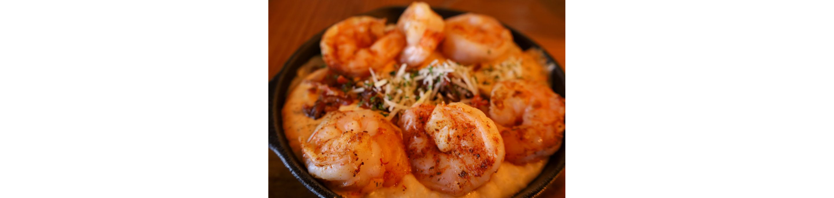 A cast iron skillet filled with shrimp and grits.