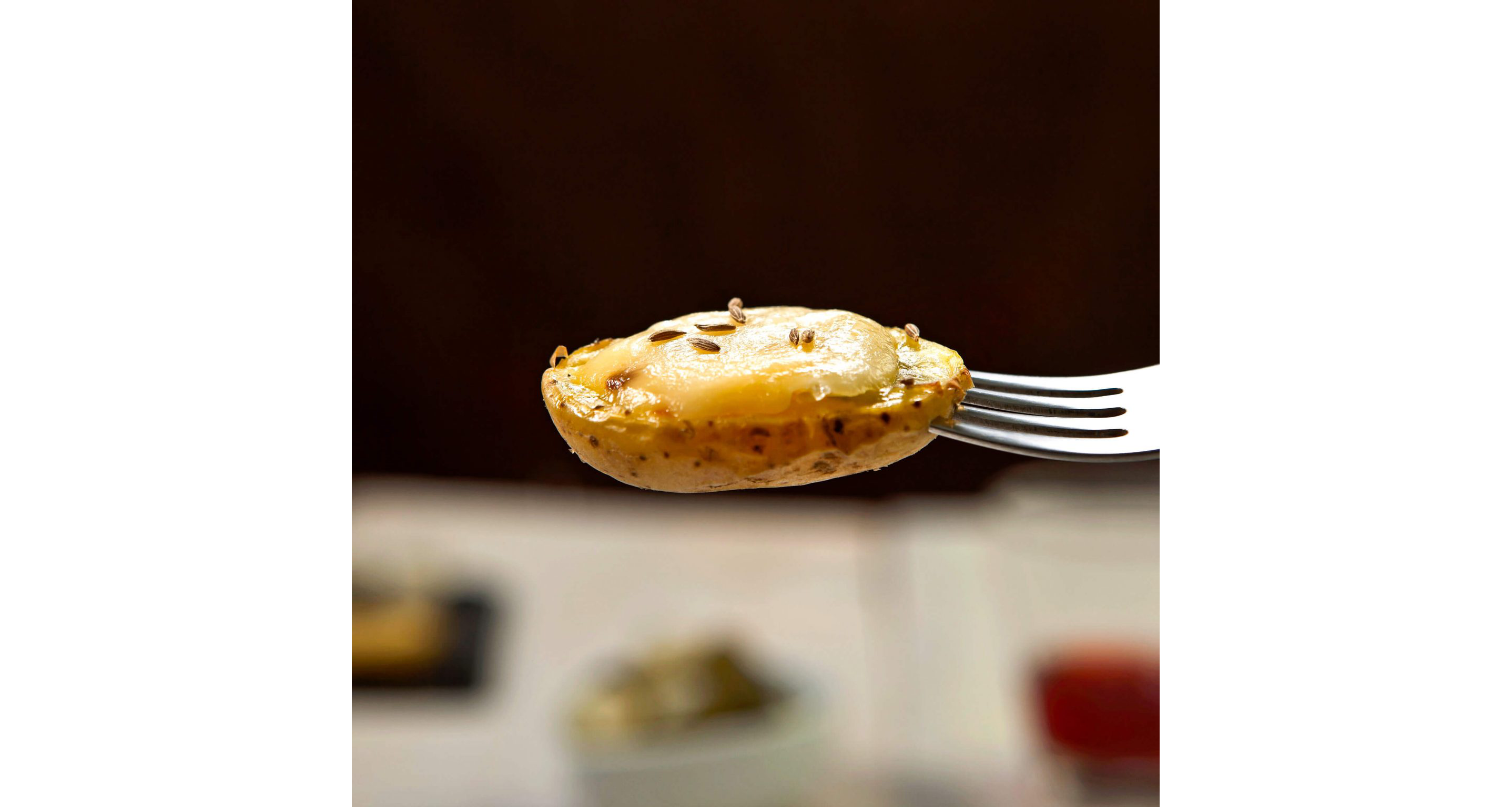 A single fork holding a small, halved potato topped with melted cheese.