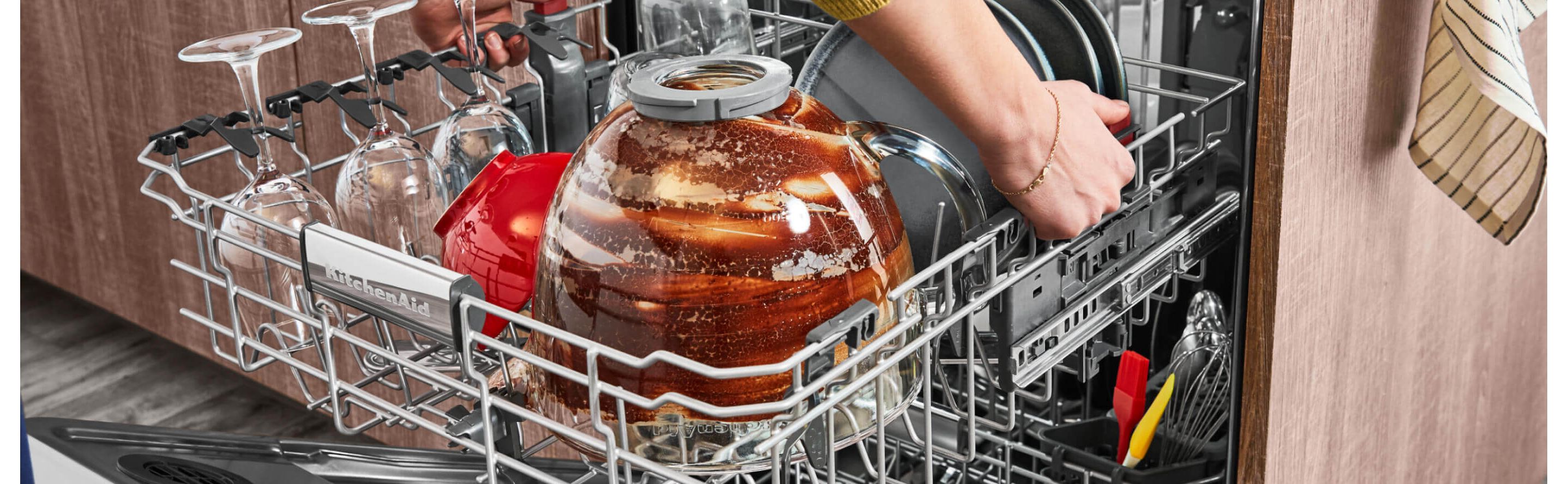 Dirty wine glasses and mixing bowl in the top rack of a dishwasher