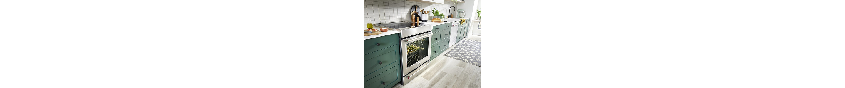 A long row of dark green cabinetry with stainless steel appliances, white countertops and white tile backsplash