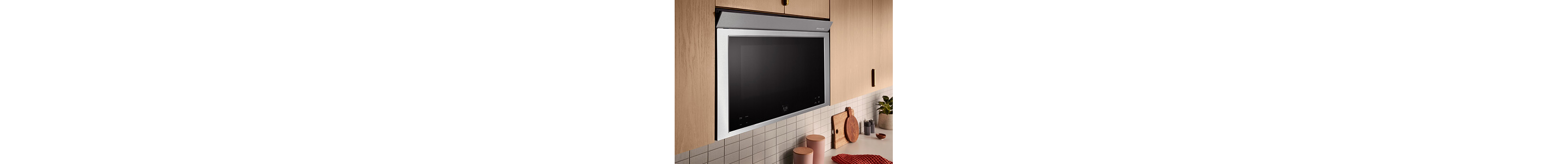 A microwave built in to upper cabinets made from light wood