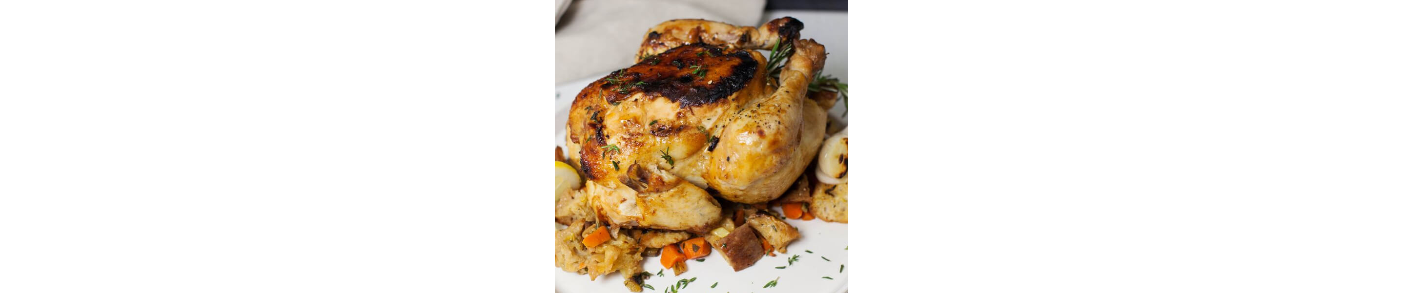 Whole roasted chicken on top of a medley of vegetables