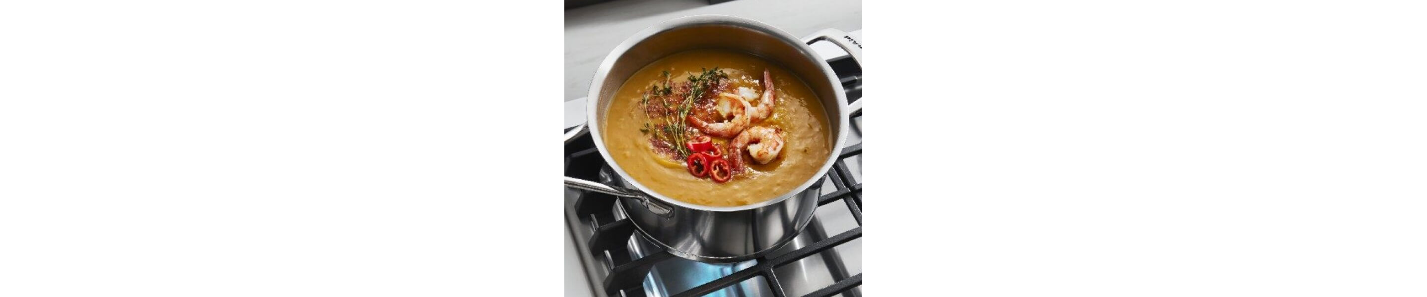 Seafood bisque simmering in a stainless steel pot on a gas stove