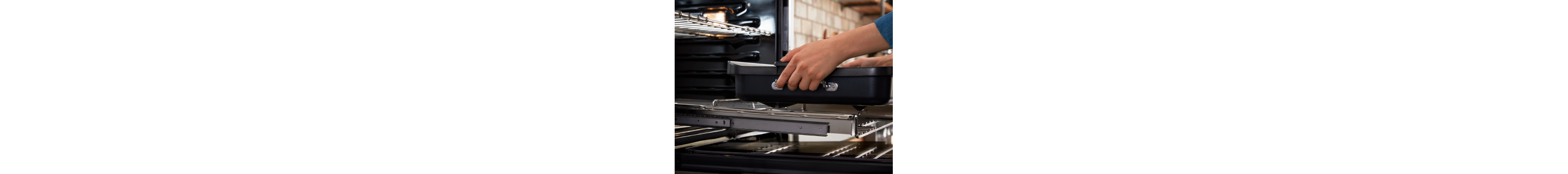 Person removing a baking dish from a wall oven slide-out rack