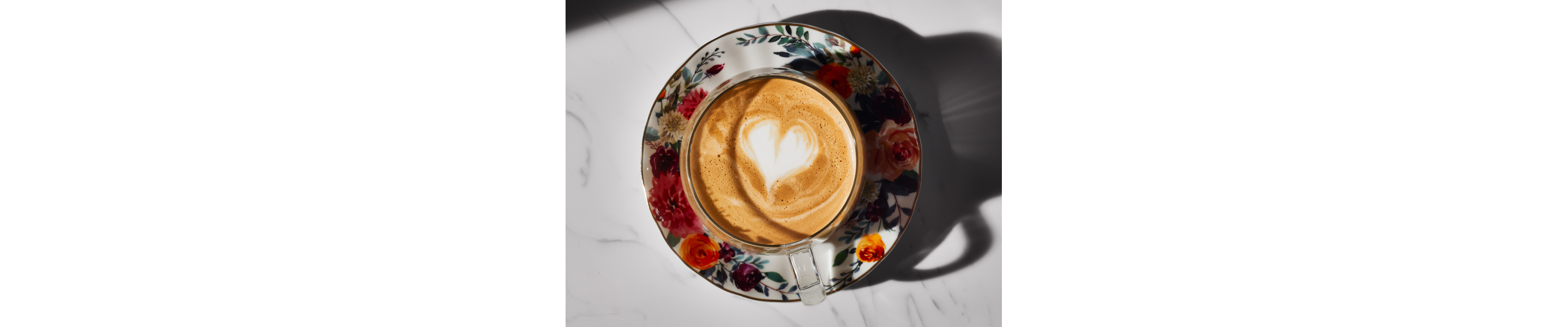 Noisette with milk foam art in teacup on ornate plate