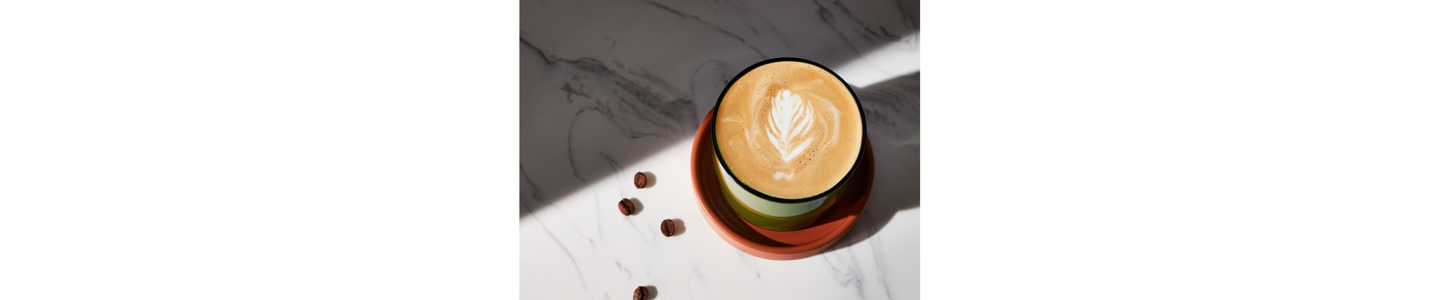 A flat white with foam art in a green cup on a granite countertop