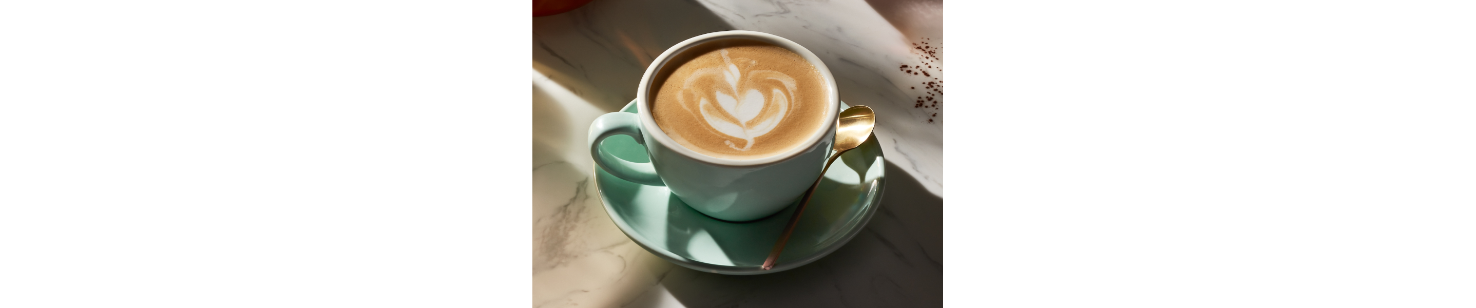 Latte with latte art in mint green tea cup on plate