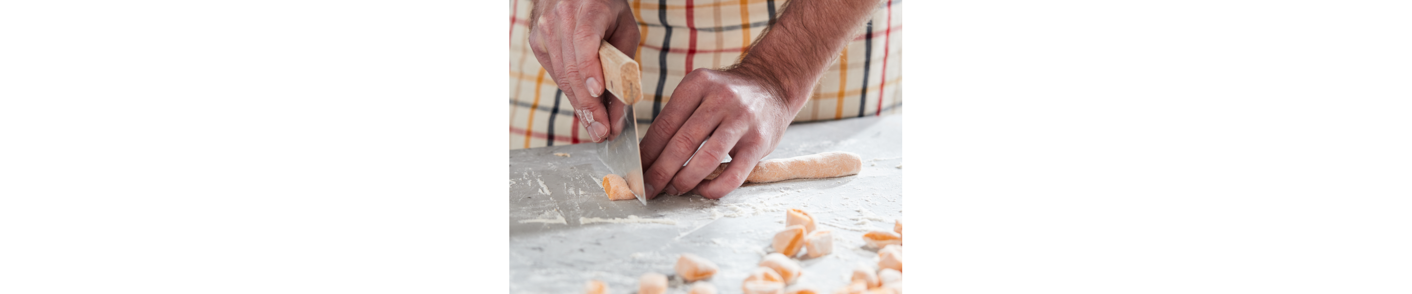 A man cutting pieces of potato gnocchi dough. 