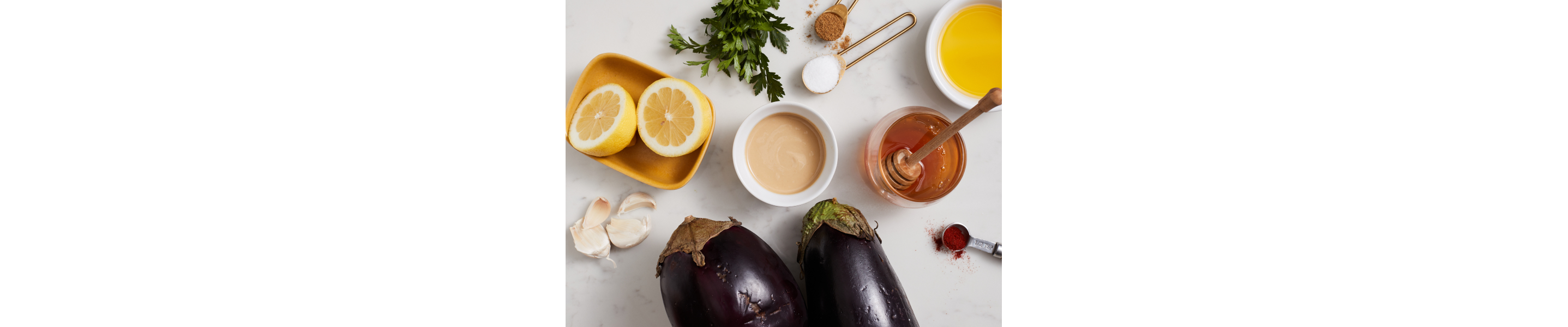 Eggplant and lemon with other baba ganoush ingredients on countertop