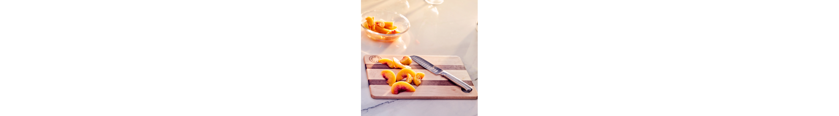 Sliced peaches on a cutting board next to a knife