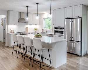 A bright white kitchen island with stool seating and pendant lights overhead