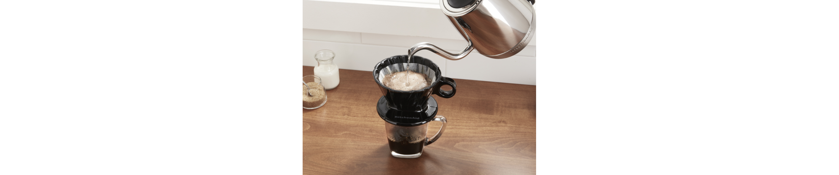 Boiled water from electric kettle being added to coffee grounds in pour over filter