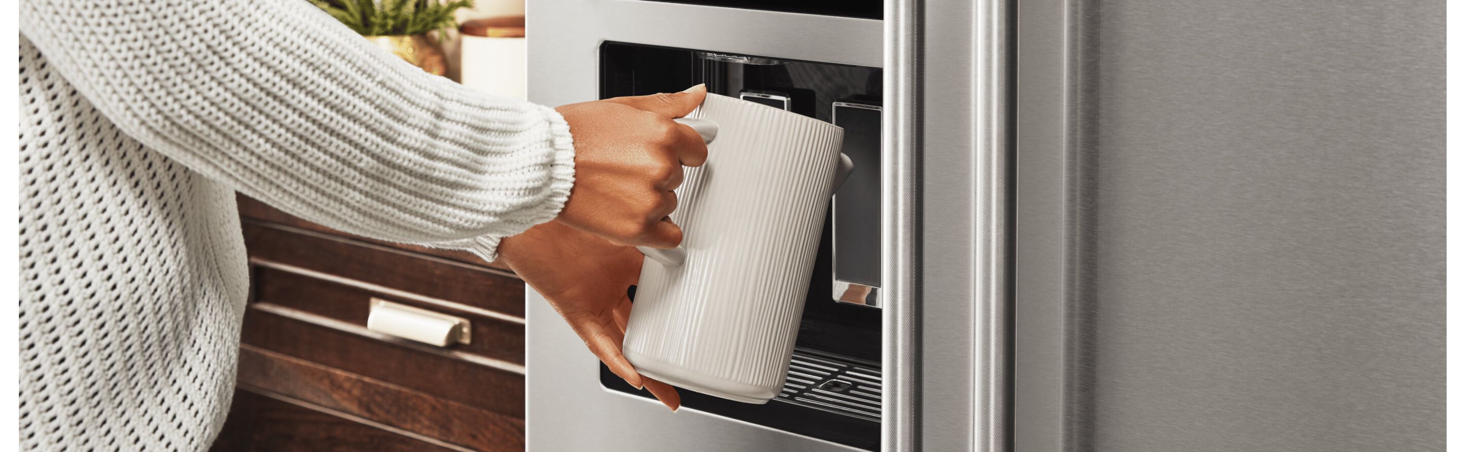 A person filling up a container at their refrigerator’s exterior ice and water dispenser