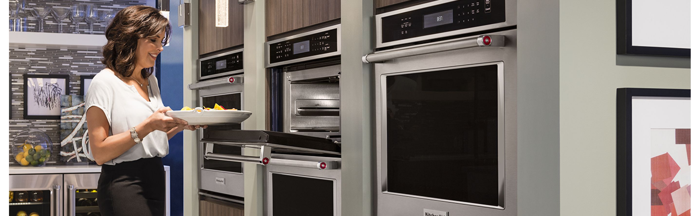 A woman placing a dish into a wall oven