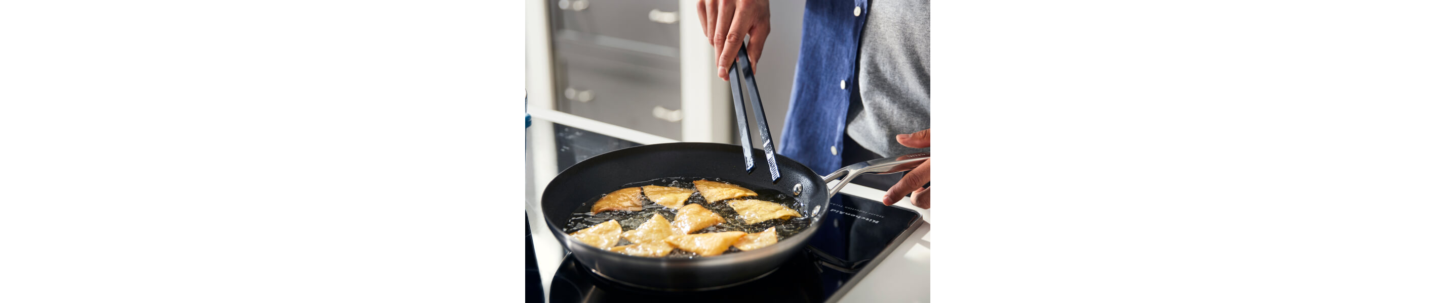 Someone frying food in a pan on their stovetop