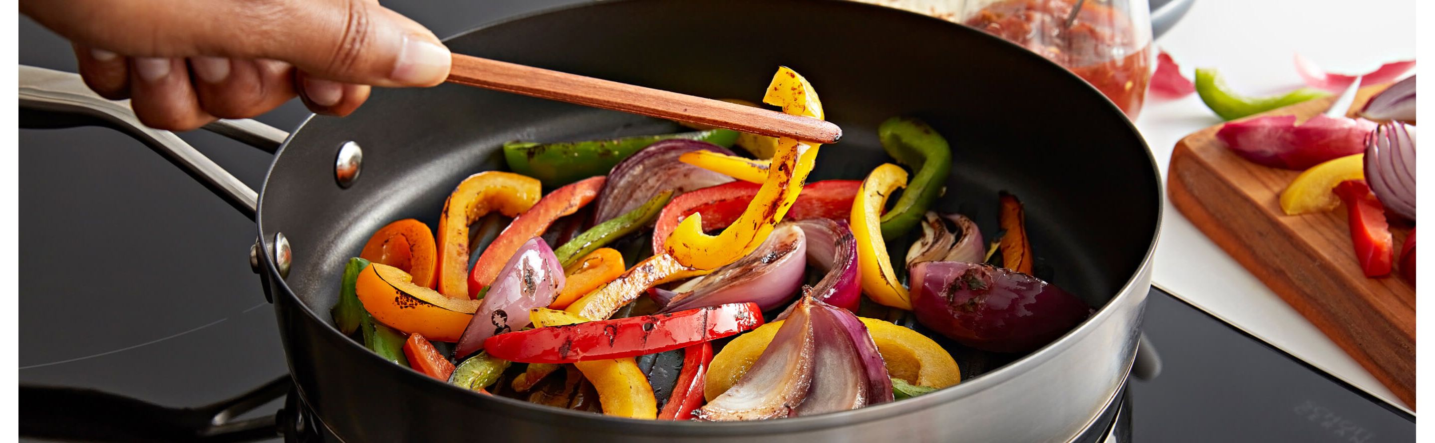 A person sauteing peppers in a pan