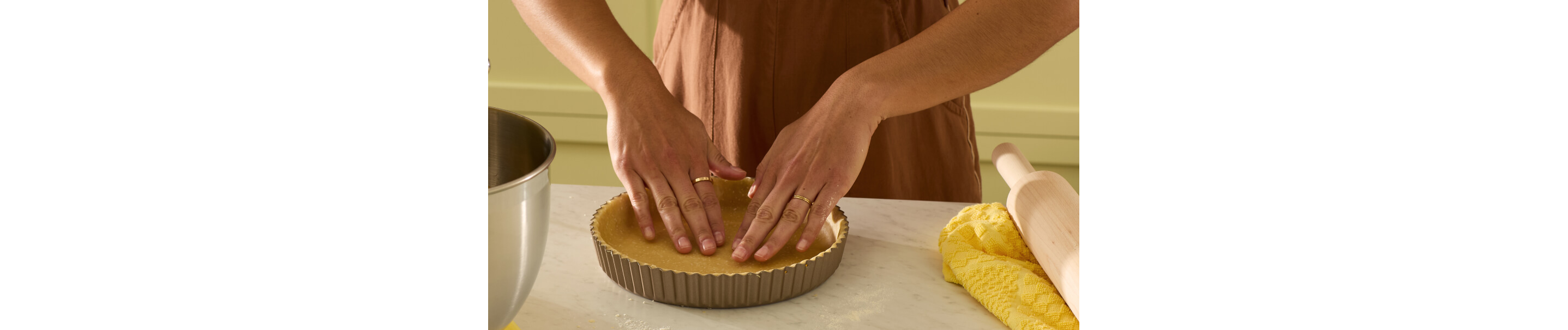 A person pressing a quiche crust into a tart pan.