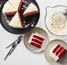 A sliced red velvet cake on a black serving tray