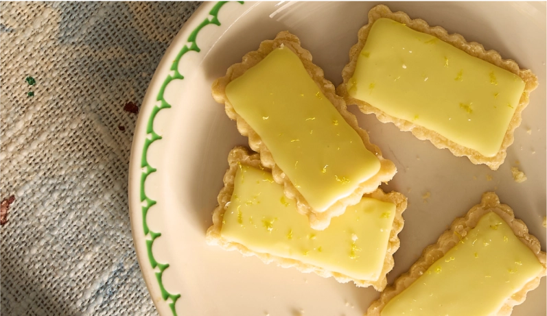 Four shortbread cookies glazed in a pale yellow yuzu glaze.