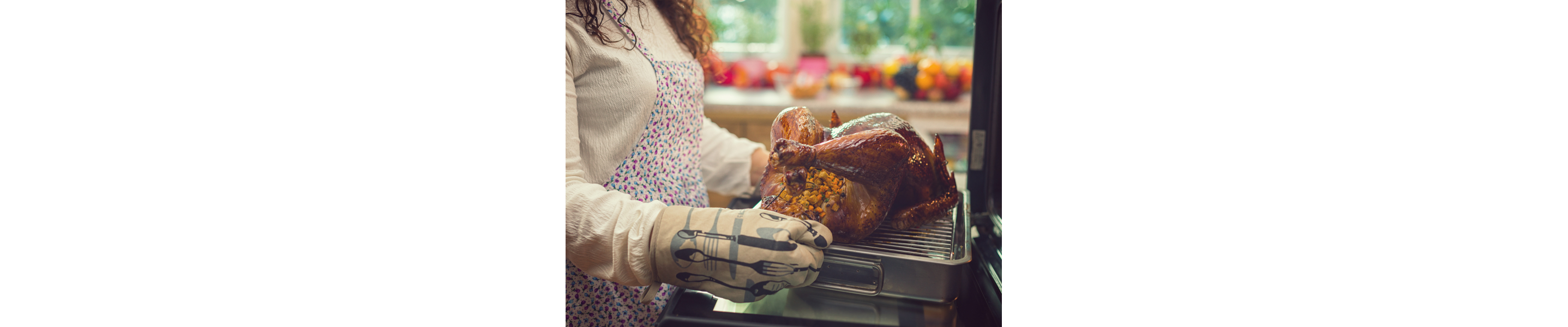 A person pulling a turkey out of a KitchenAid® wall oven