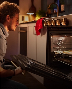 A person about to pull a dish out of the oven.
