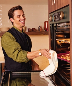 Chef Antoni Porowski removing a pan from a KitchenAid® wall oven